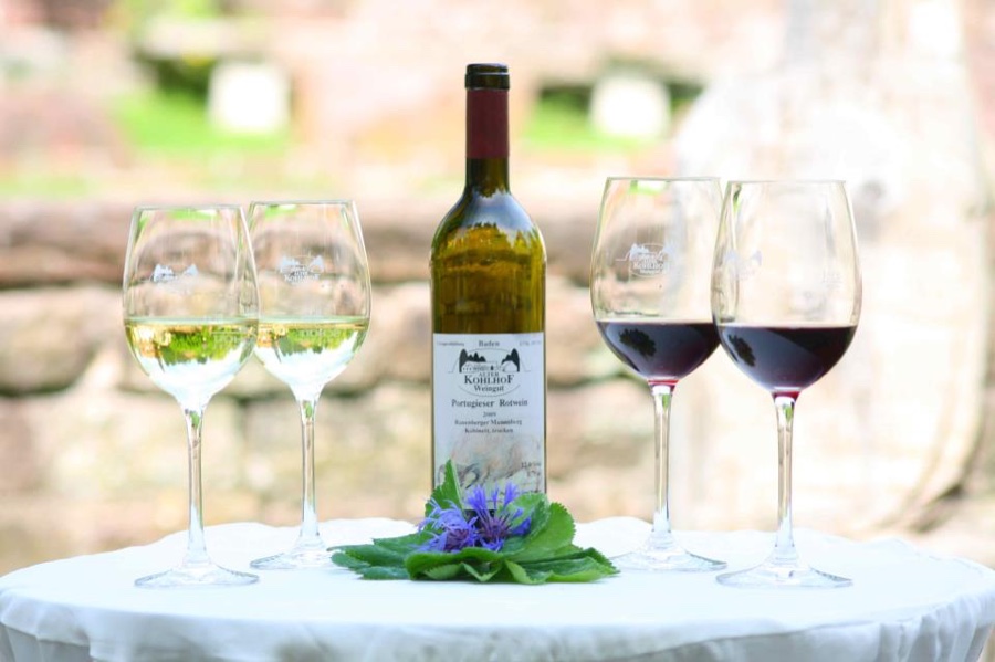 Weingläser mit Rot- und Weißwein neben einer Flasche vom Weingut Alter Kohlhof